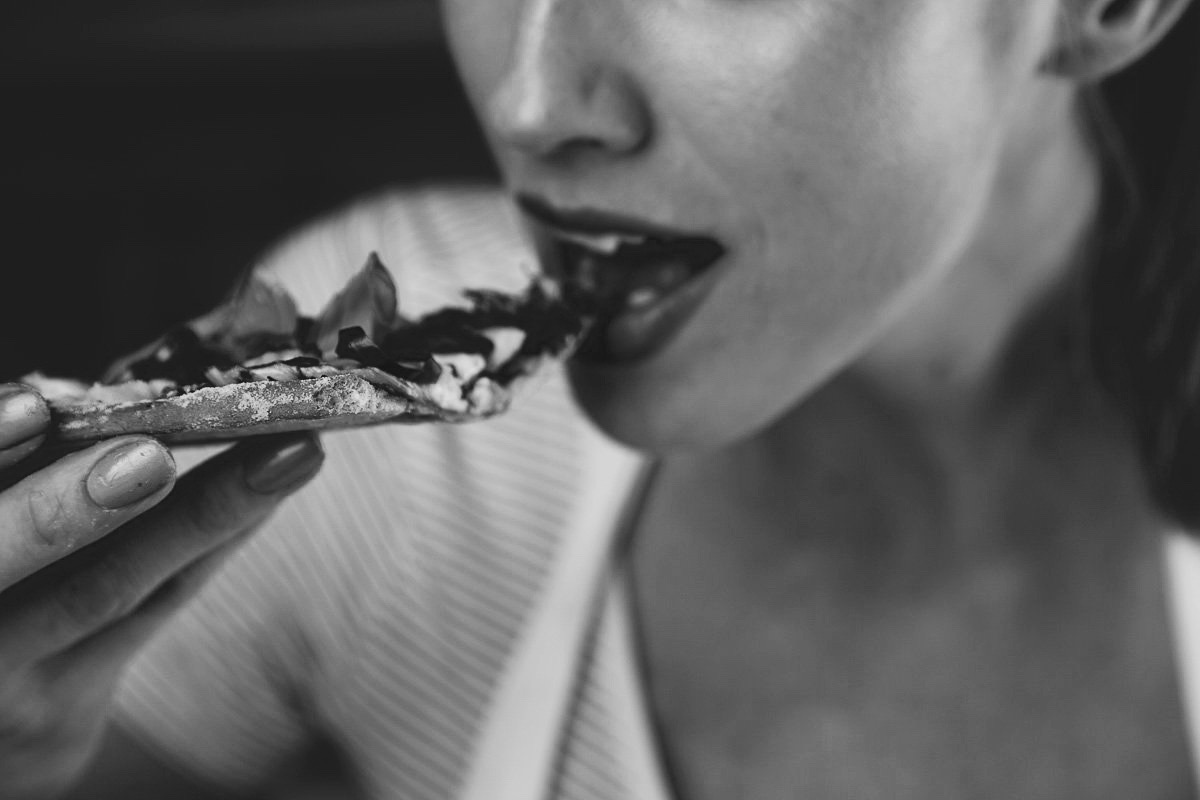 woman eating a slice of delicious pizza | sultryvegan.com