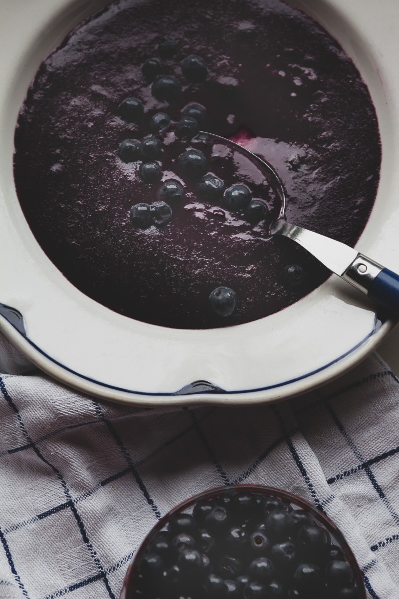 bilberry graham porridge on a traditional white plate with a side of fresh wild blueberries