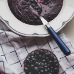 blueberry rye porridge on a traditional white plate and a bowl of fresh wild blueberries