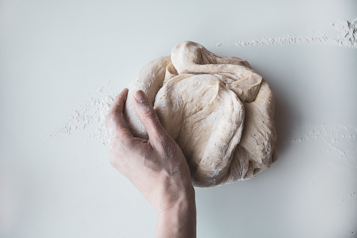 a hand kneading vegan cinnamon bun dough