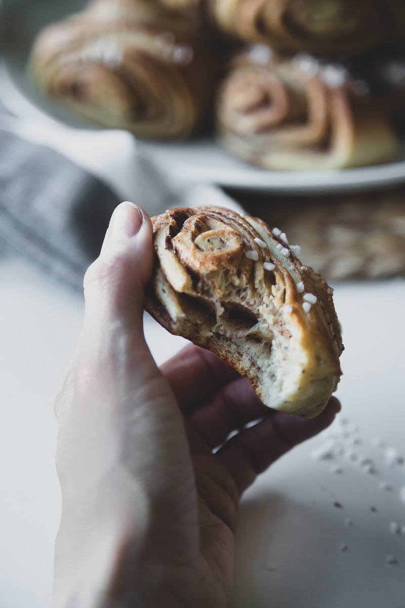 a hand holding a freshly baked vegan finnish cinnamon bun