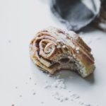 freshly baked vegan cinnamon bun that someone has taken a bite off of