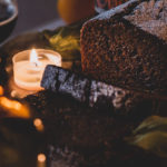 Vegan Christmas Loaf Cake sliced on a decorated cutting board with candles and a glass of dark beer