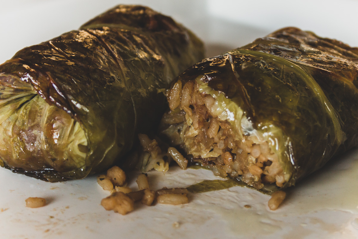 Close up of two baked savoy cabbage rolls on a white plate.