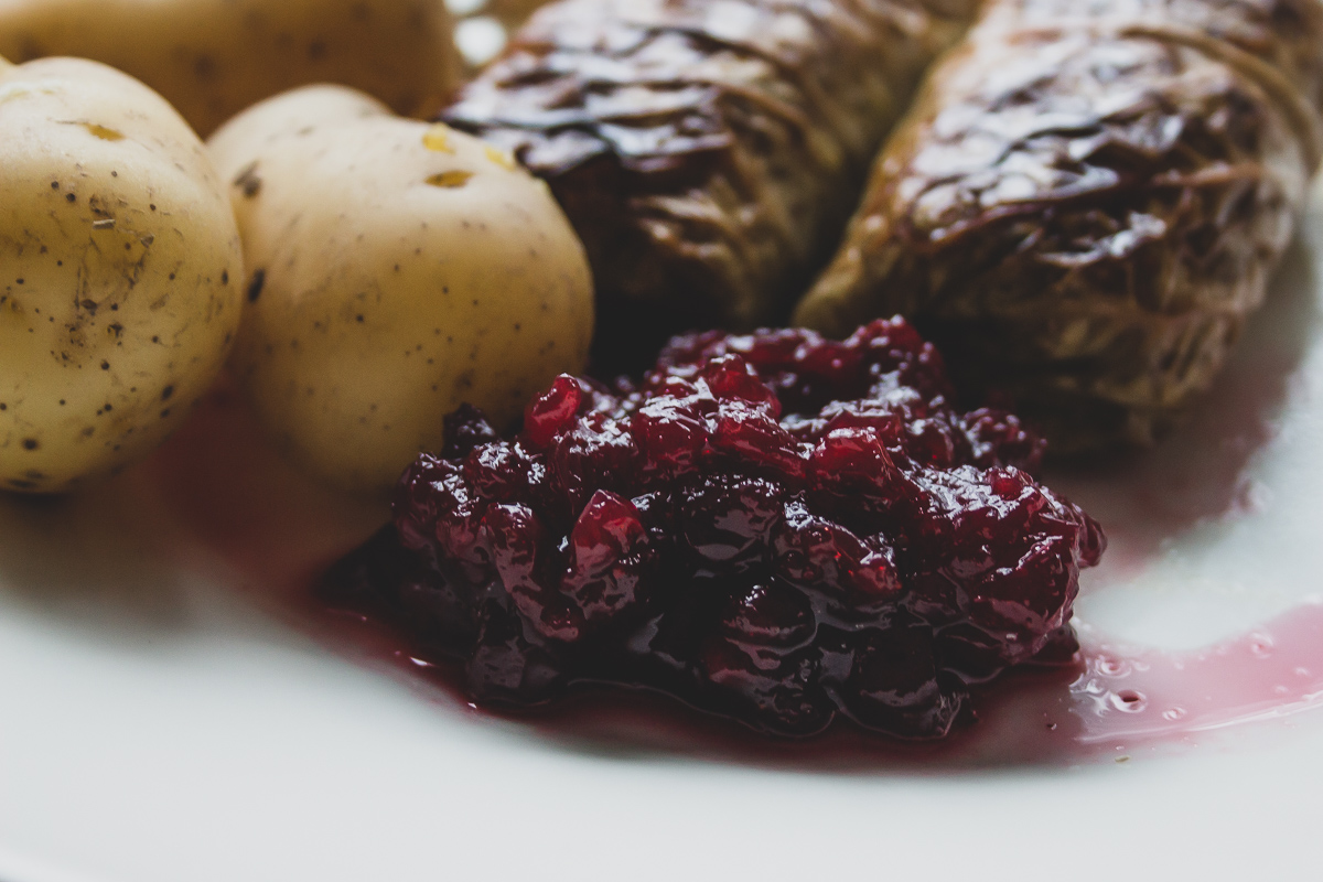 Savoy cabbage rolls plated with lingonberry jam and boiled potatoes.