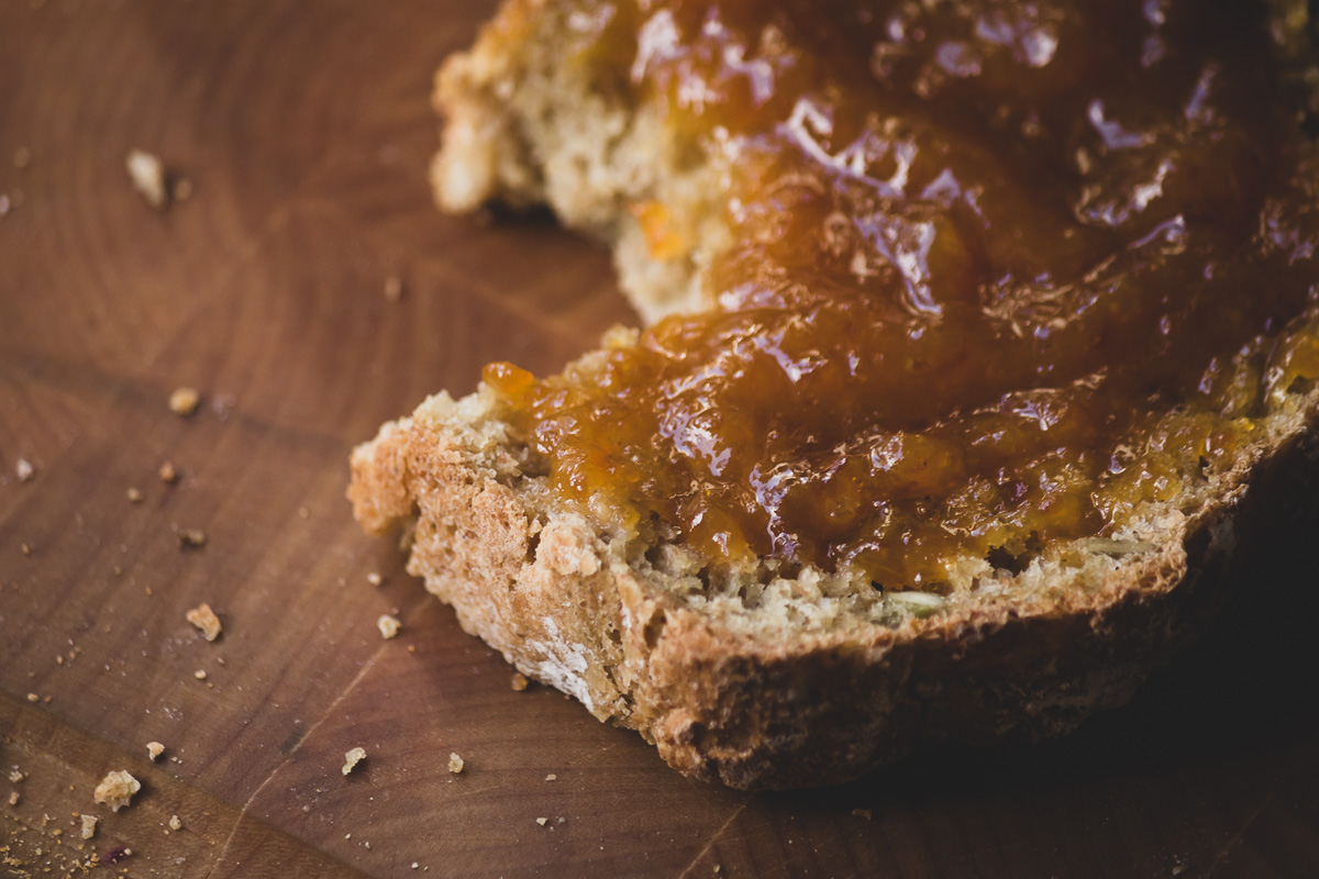 A close up of a slice of breakfast bread, topped with mandarin marmalade & bread crumbs.