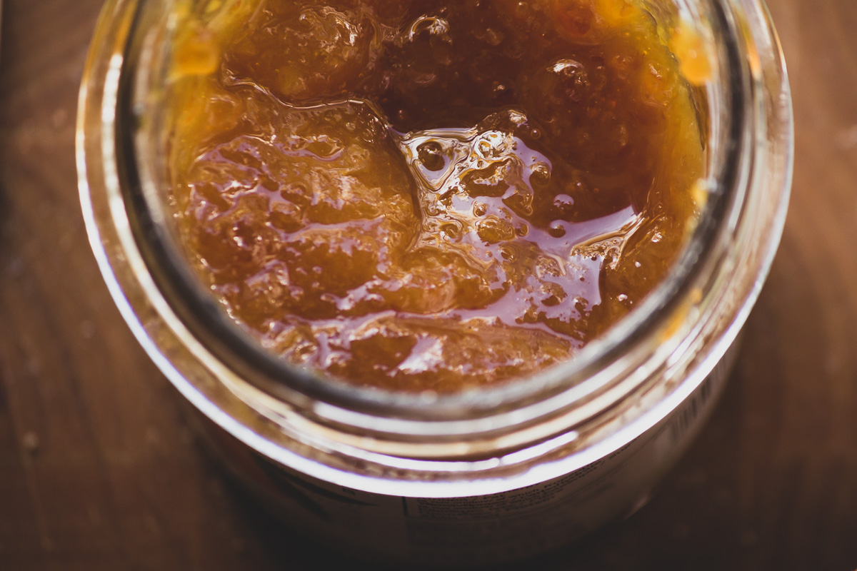A close up of a glass jar of mandarin marmalade.