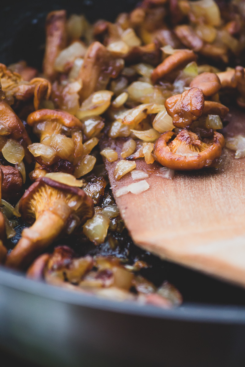 A close up of a pan with Chanterelle mushrooms and chopped onion.
